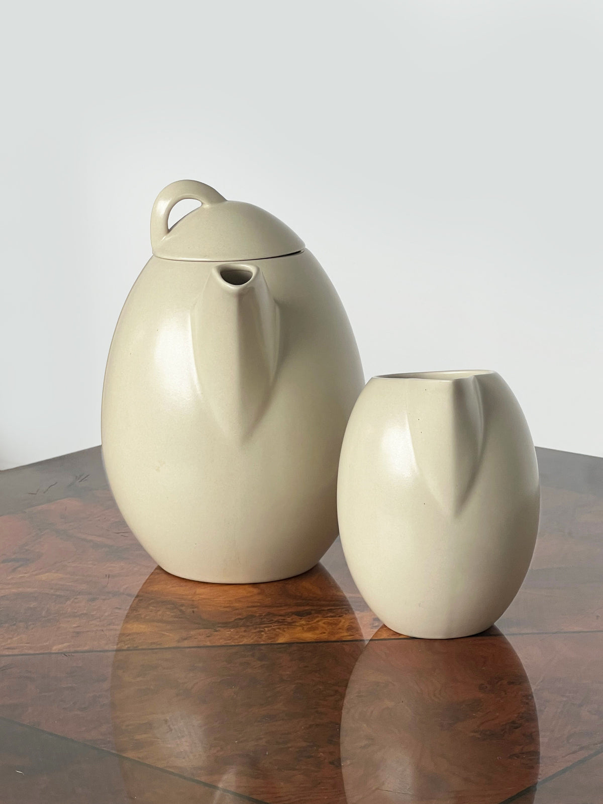 Cream ceramic teapot and milk jug set on wooden surface