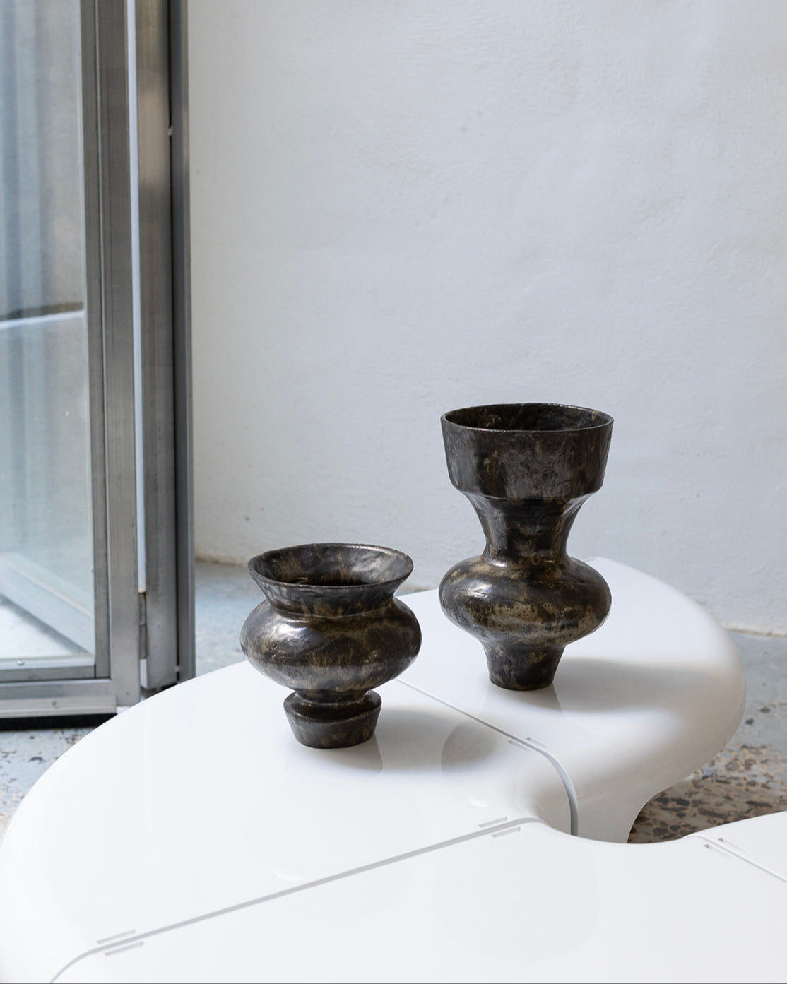 Two dark obsidian glass vases with curved silhouettes on white surface