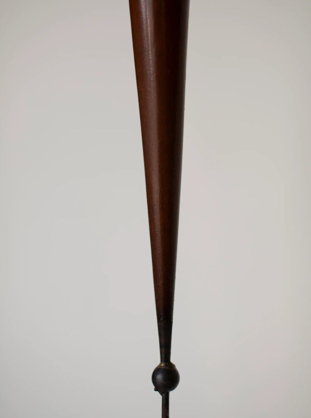 A close-up image of a wooden cone-shaped object tapering down to a small spherical metal base. The background is a plain off-white color, placing emphasis on the shape and texture of this Set of Copper Candle scones by Pieter Spruyt 1980s, available from CU-RA-TED.
