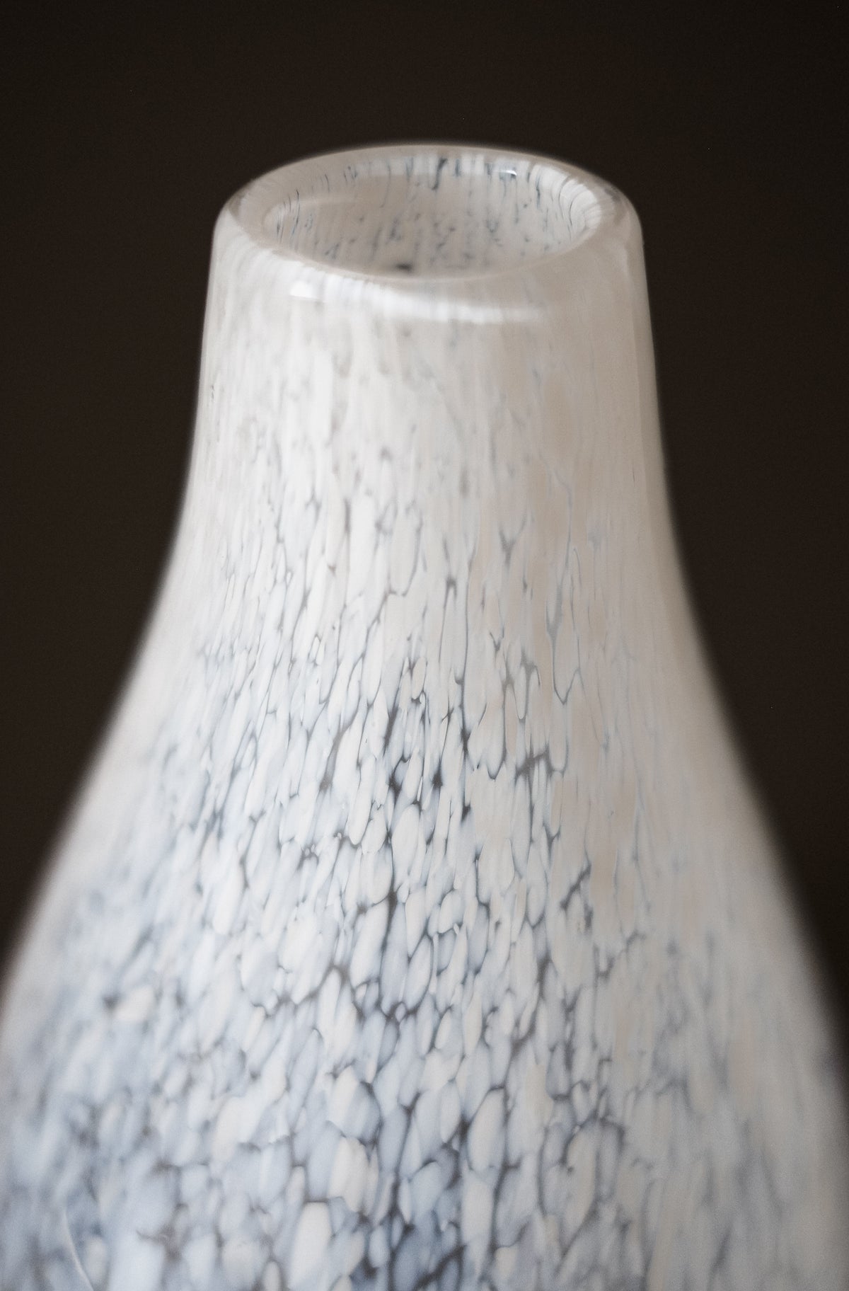 Close-up of the upper part of the White Vase Tortoise Glass by septembre studios, featuring a smooth white finish, a narrow neck, and a delicate gray speckled pattern against a dark background.