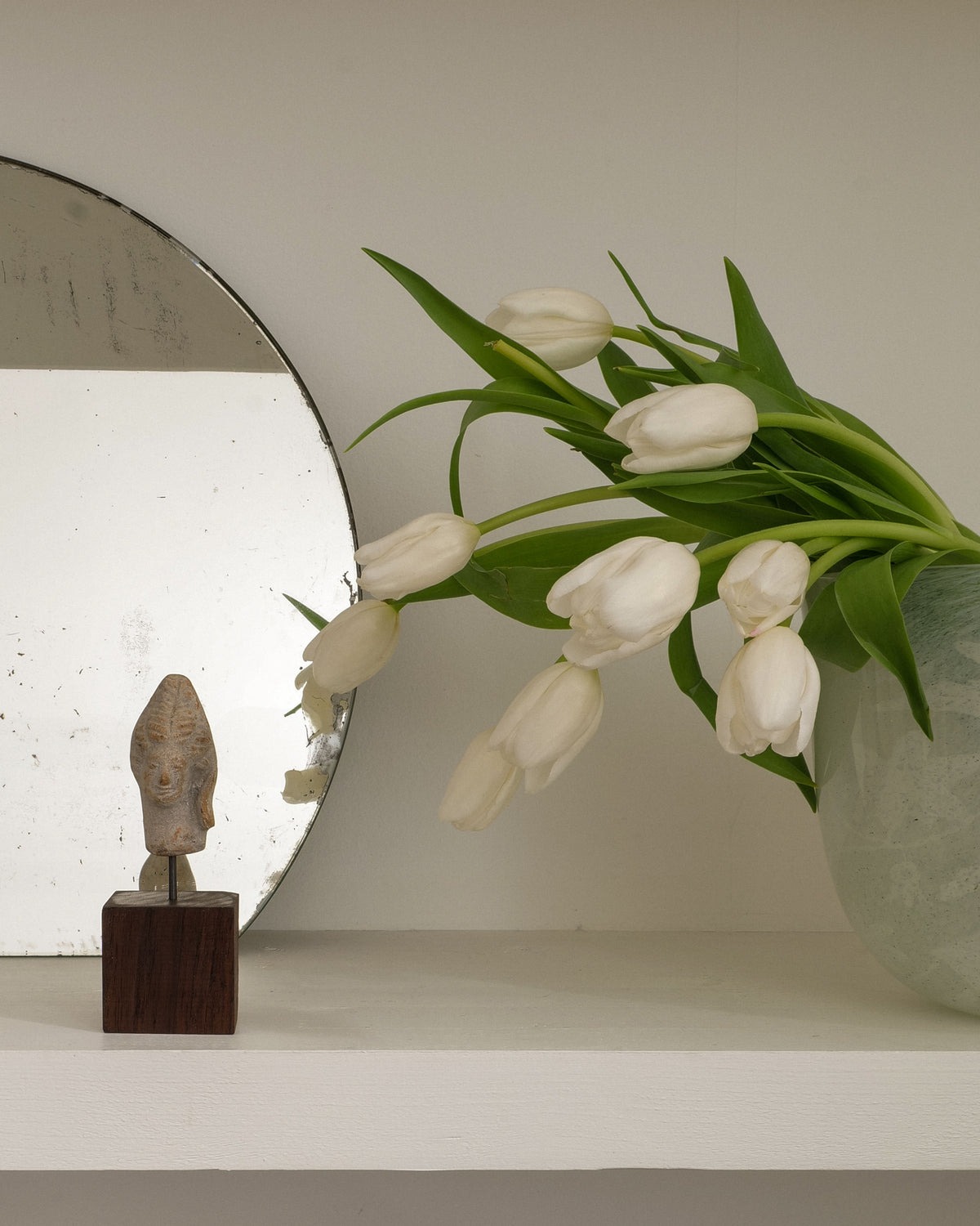 Hera ancient sculpture with white tulips in minimalist setting