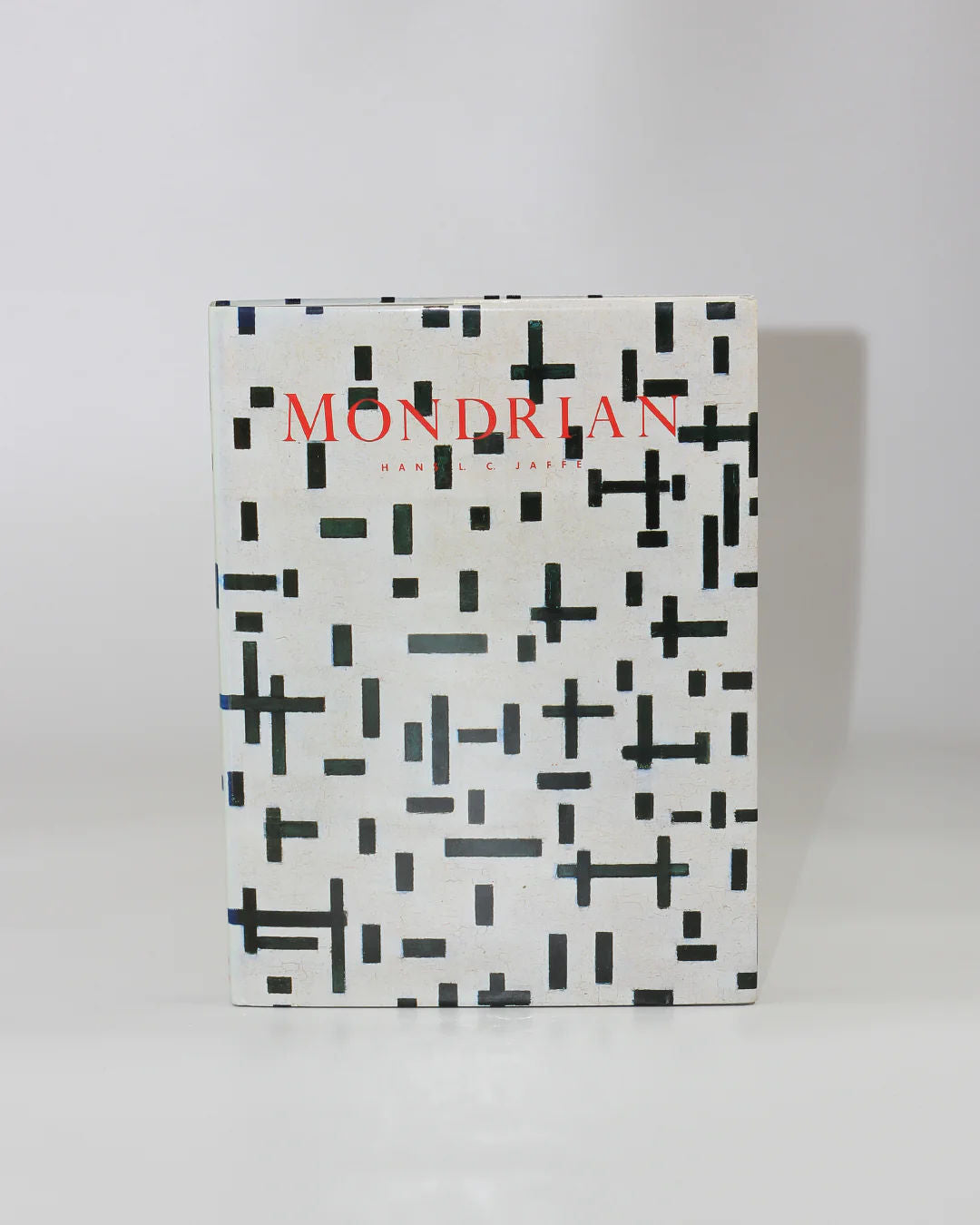 The book cover for "Mondrian" by Hans L.C. Jaffé from Boga Avante Shop features abstract black and white geometric patterns inspired by Piet Mondrian's neoplasticism, with bold red text at the top embodying abstract art's essence.