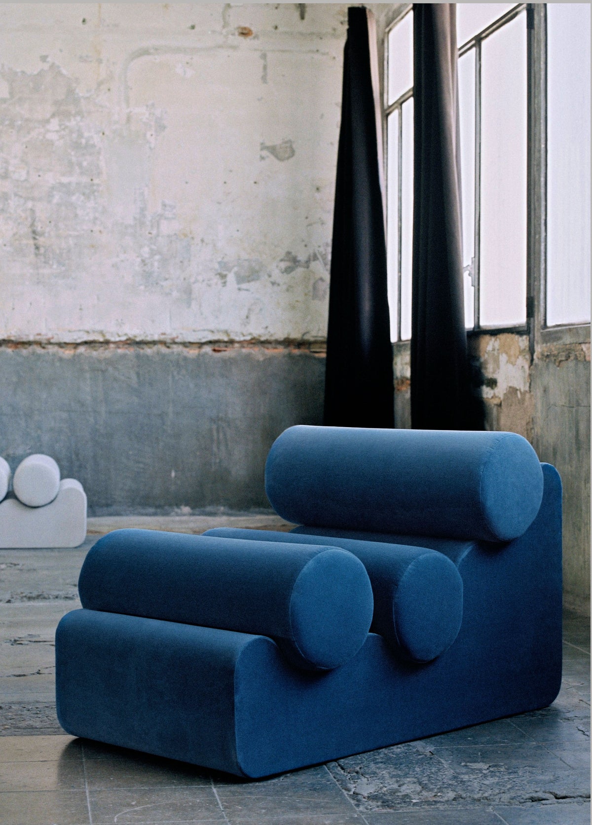 Blue cylindrical cushion lounge chair in industrial interior setting