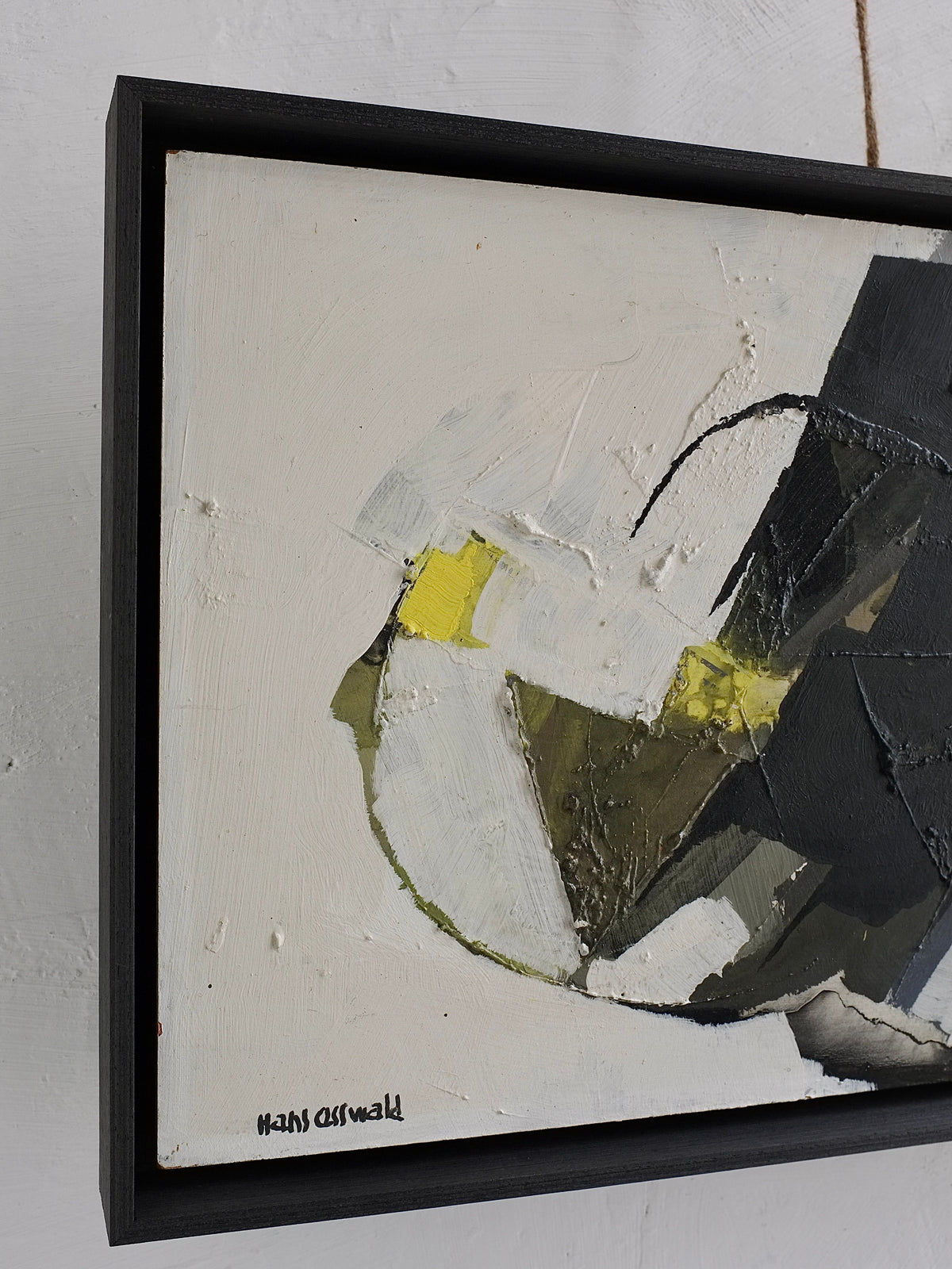 A close-up of the Abstract Oil Painting by Hans Osswald, Sweden 1950s from Veter Vintage, showing textured white, black, yellow, and gray shapes in a black frame. The artist's signature appears in the bottom left corner.