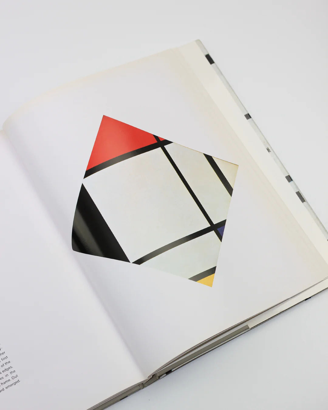 The "Mondrian" by Hans L.C. Jaffé from Boga Avante Shop is an open book with a cut-out page revealing a geometric design underneath, featuring intersecting black lines and white, red, and yellow blocks in a neoplastic abstract art style.