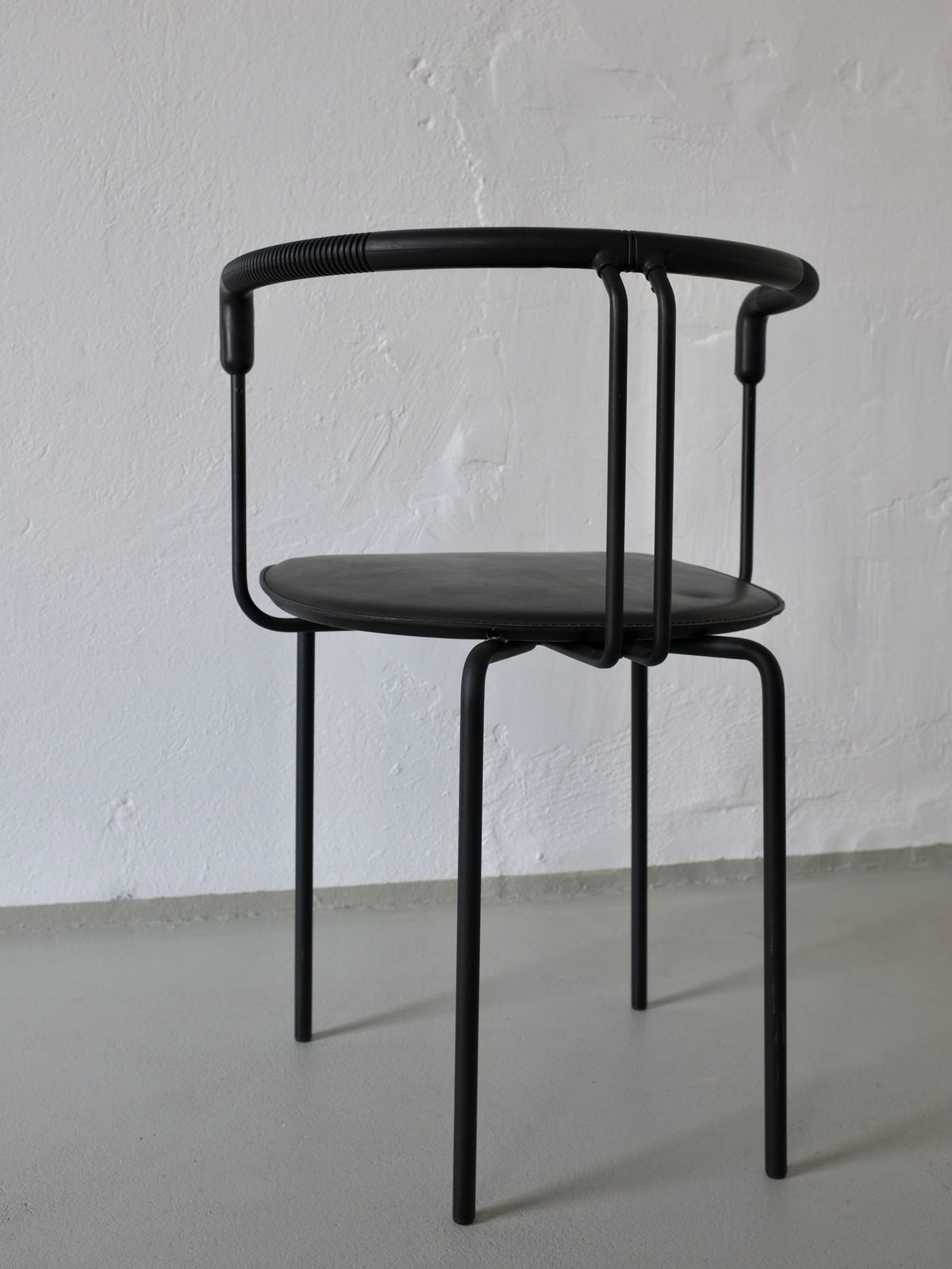 Single black leather postmodern armchair with curved backrest