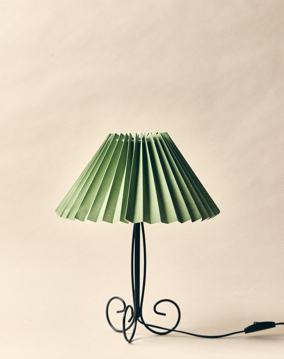Pise table lamp with pleated green shade and curved black metal base