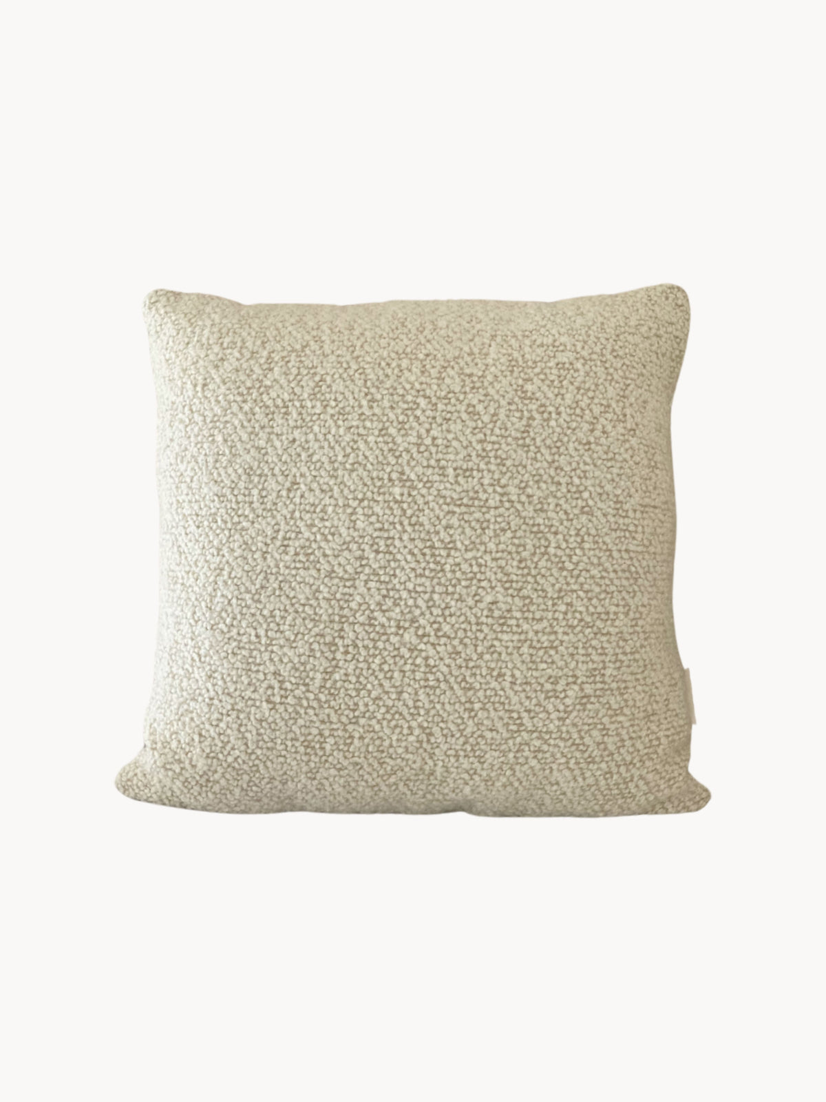 A square, off-white textured cushion with a plush and soft appearance. This handmade Le Carré - Wool Bouclé - Sawdust/Eggshell cushion by AMÉLIORÉ features British eco wool, giving it a clean and minimalist look. The absence of visible patterns or designs enhances its vintage-inspired appeal.