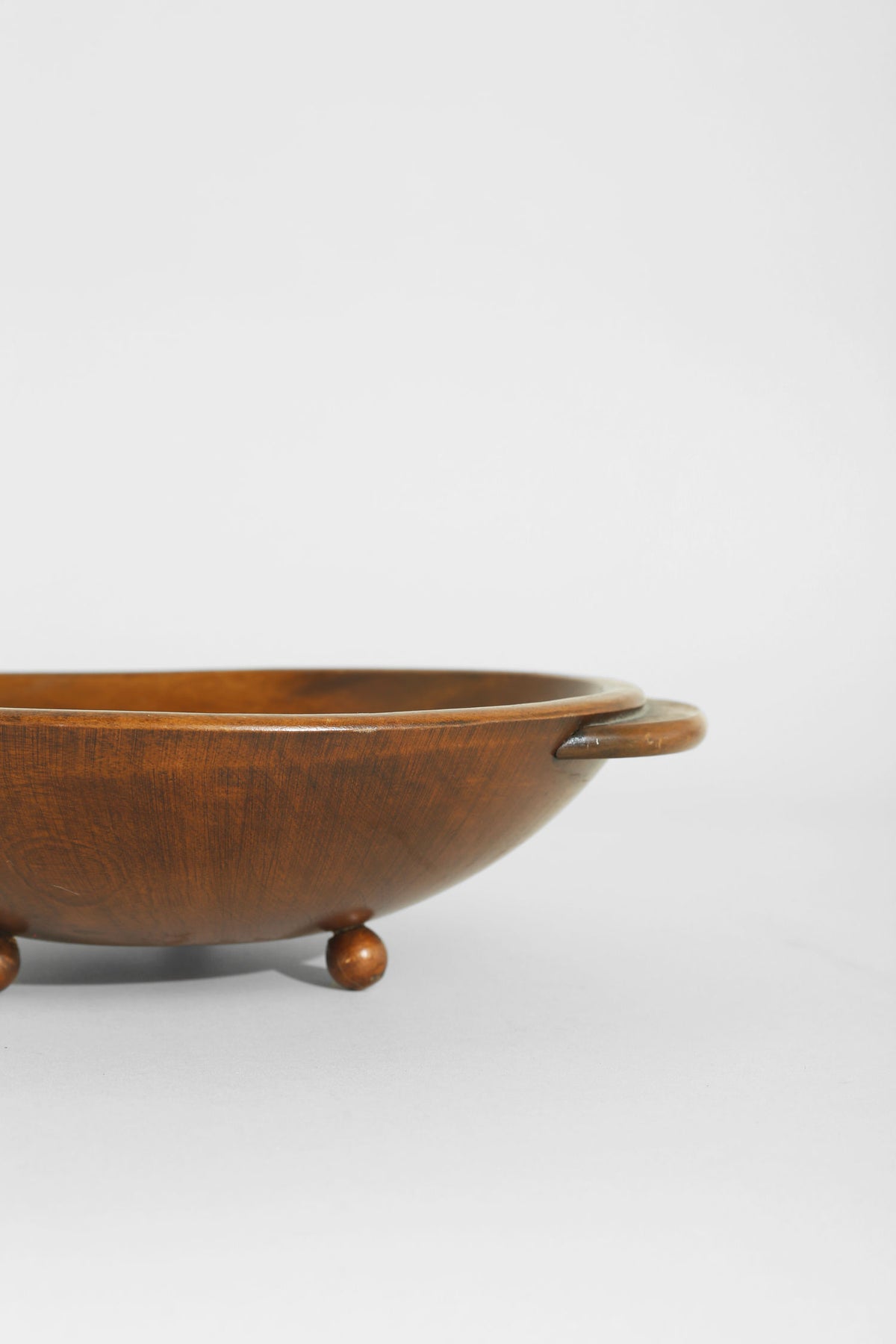 Folk wooden bowl with handles on decorative ball feet, profile view