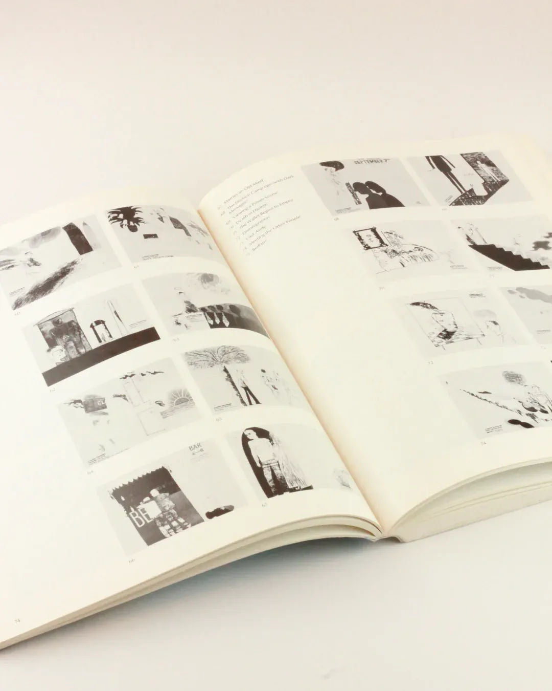 An open David Hockney 'My Early Years' by Boga Avante Shop lies on a flat surface, displaying pages with multiple grayscale sketches and illustrations. The images in the book, reminiscent of David Hockney's style, are a mixture of abstract and figurative artwork. The background is a plain, light-colored surface.