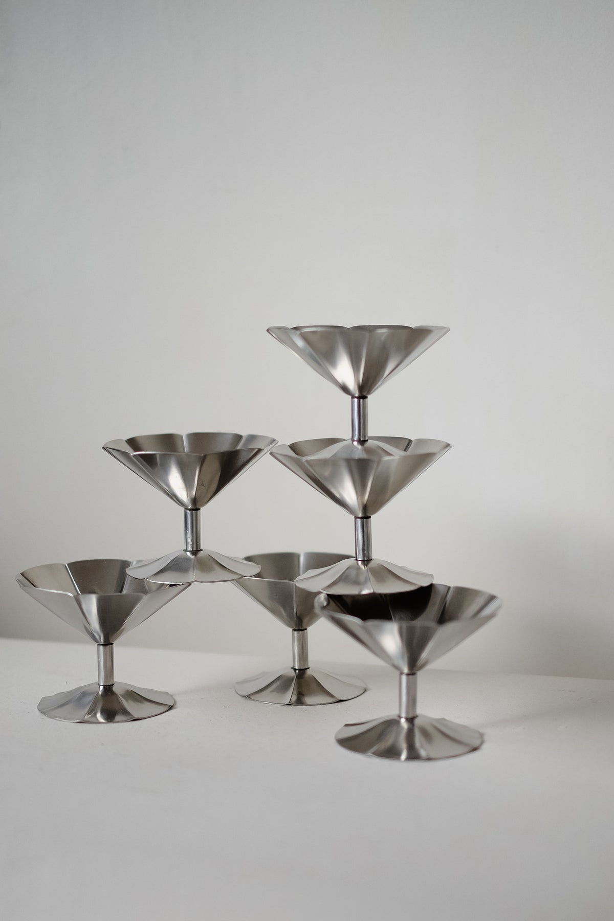 A minimalist arrangement of six septembre studios' Ice Coupes stacked in a pyramid on a white surface against a plain background.