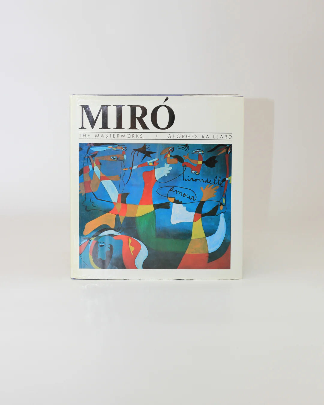 Book cover of "Mirò The Masterworks" from Boga Avante Shop, showcasing an abstract painting with vibrant blue, red, orange, and yellow shapes. The light background highlights the modern art and surrealism of Joan Mirò's style.