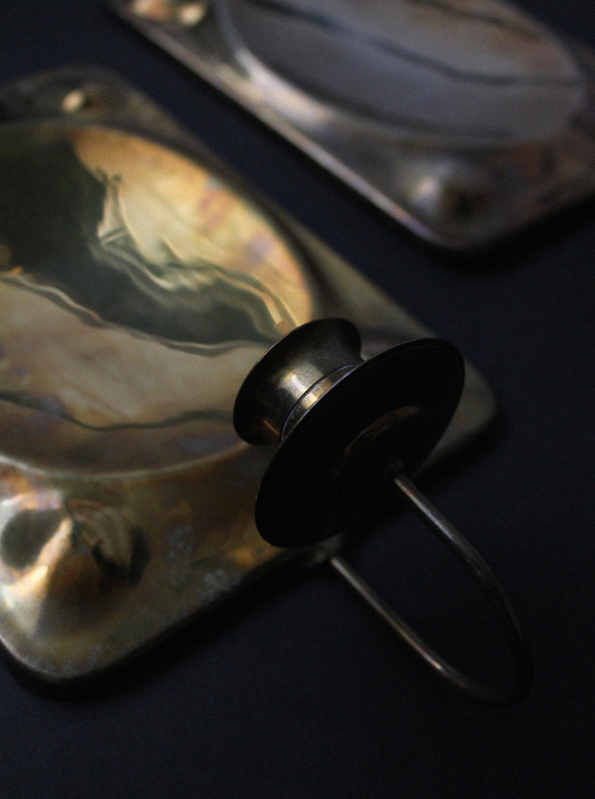 Close-up detail of brass candle sconce with black knob handle