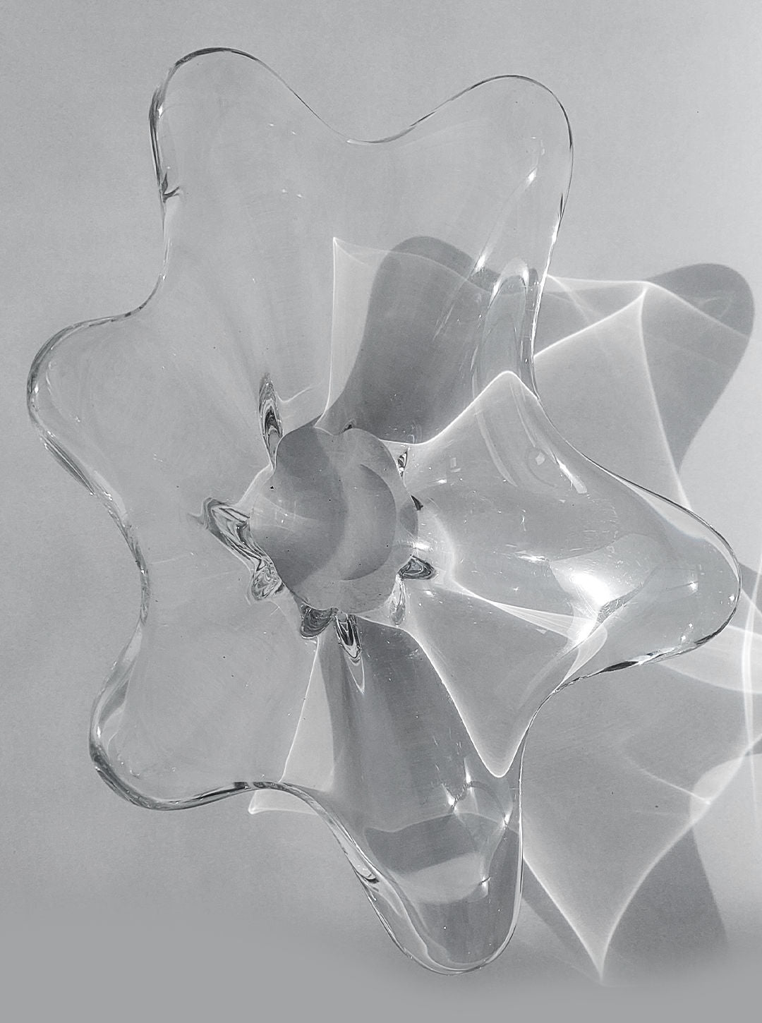A top view of the Crystal Baccarat Cup by Les Objoies highlights crystal artistry, casting intricate light and shadow patterns on a gray surface.