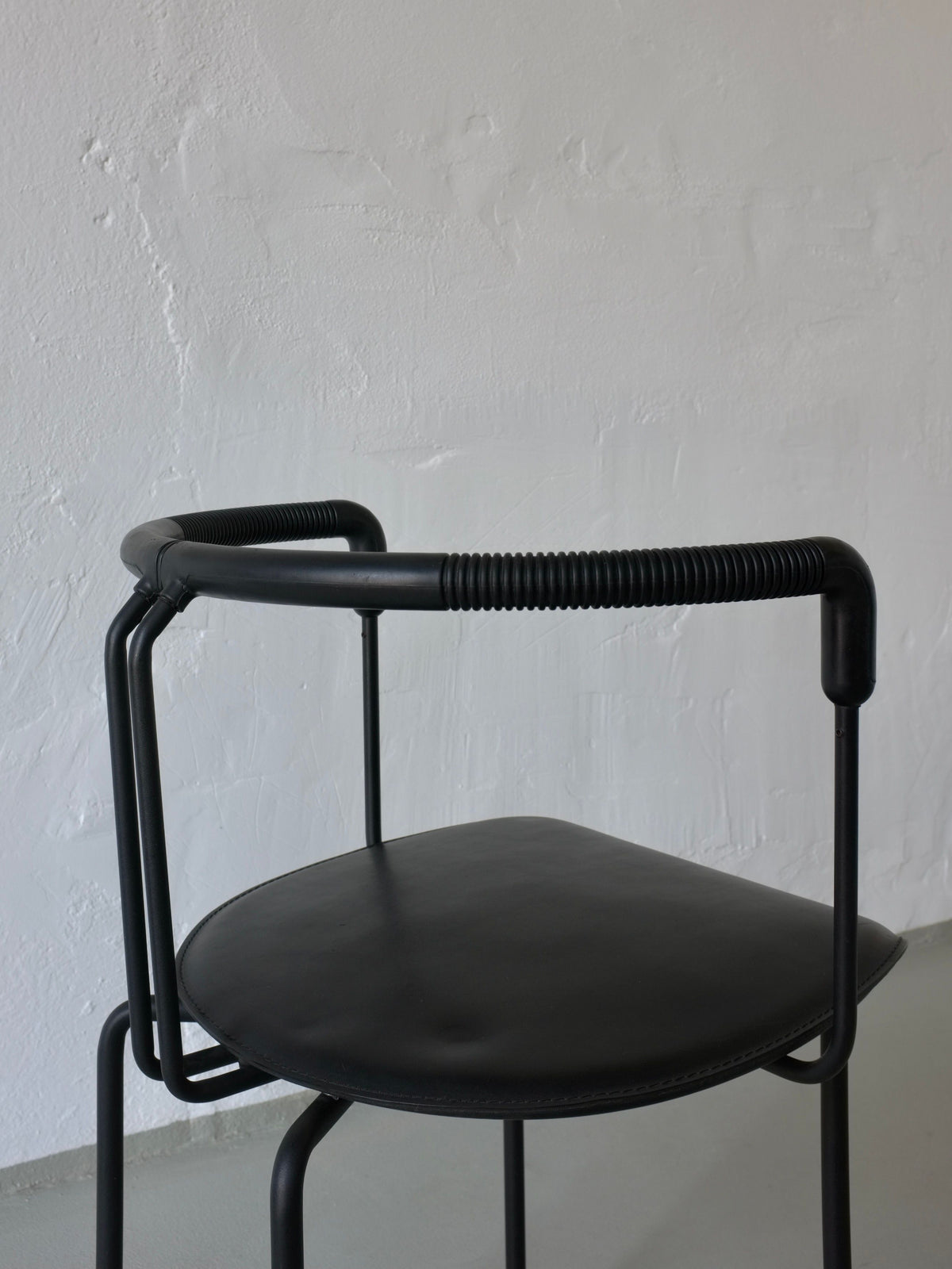 Close-up detail of black leather seat and tubular metal frame