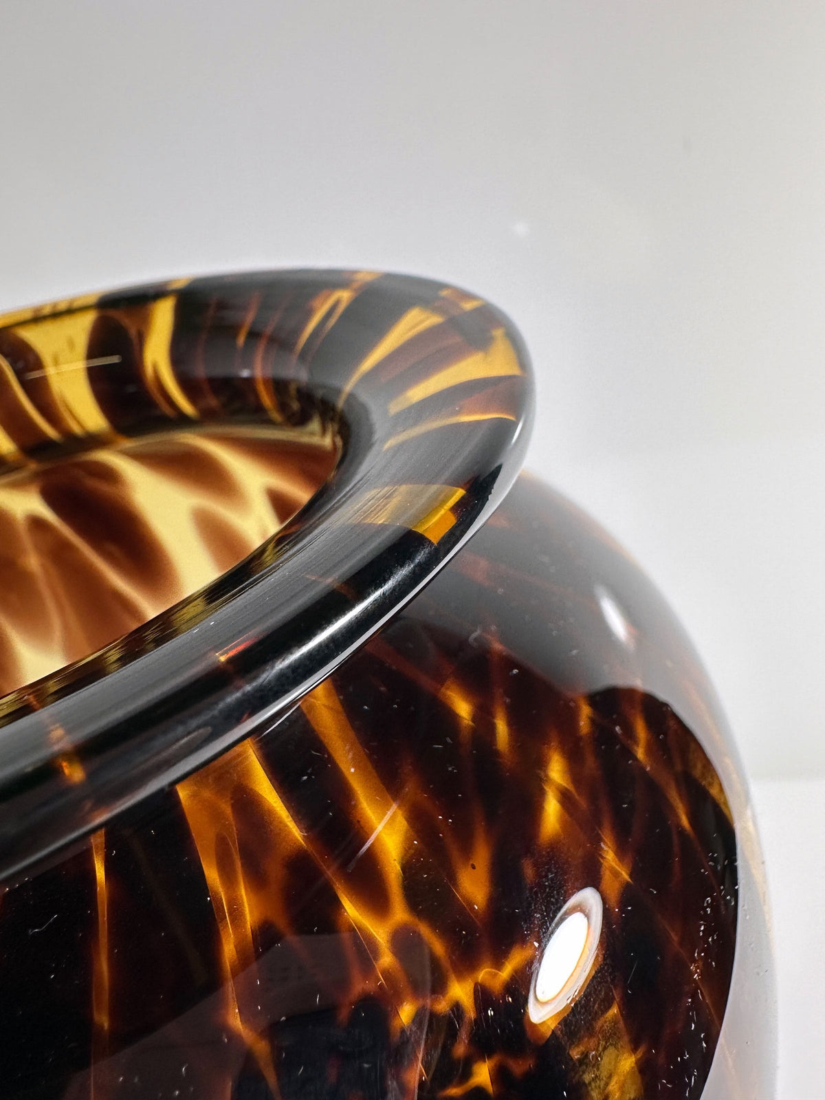 A close-up of the Tall Murano Tortoise Vase by Dodo Vintage, crafted with a glossy tortoiseshell pattern. Set against a white background, it showcases intricate amber and dark brown swirls and a reflective surface reminiscent of an exquisite vase.