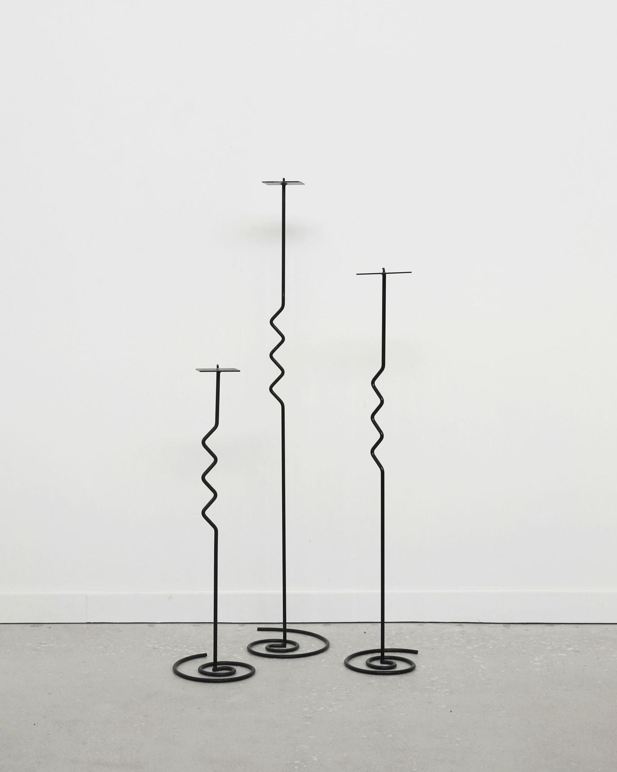 Three black metal spiral floor candleholders of varying heights