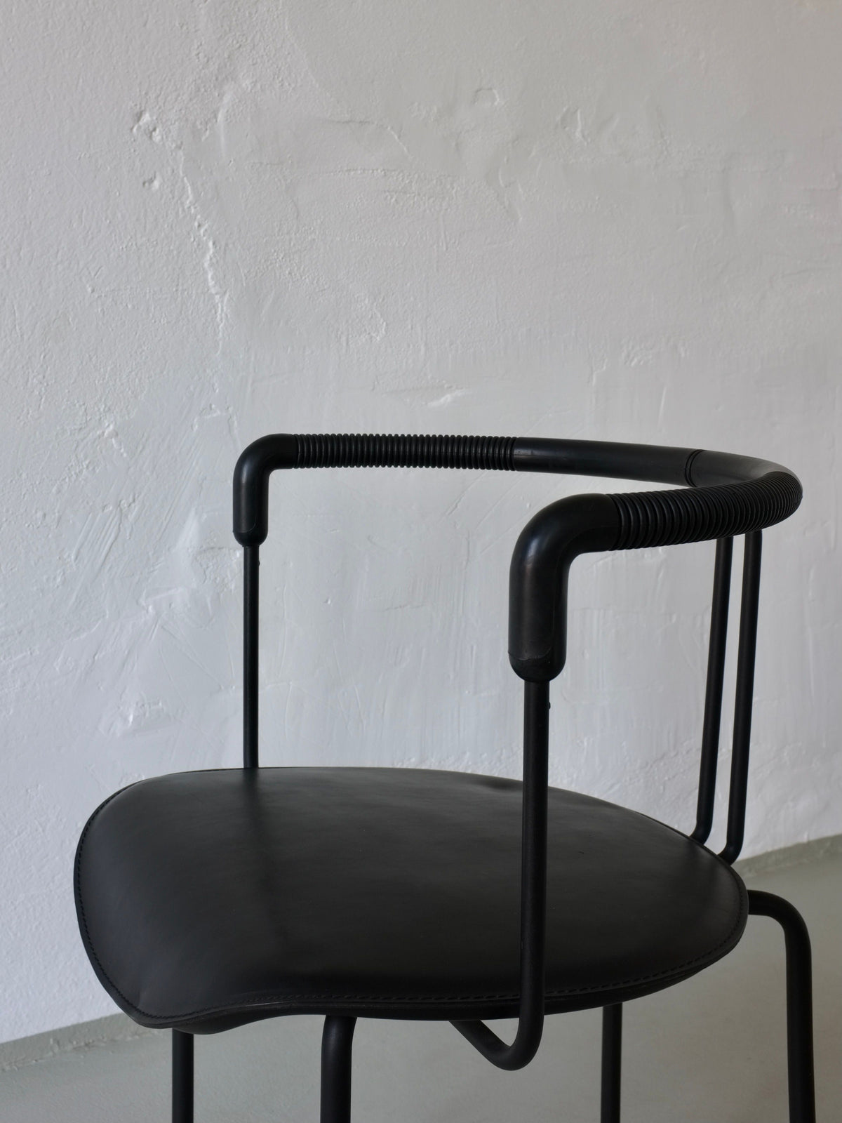 Close-up detail of black leather seat and tubular armrest structure