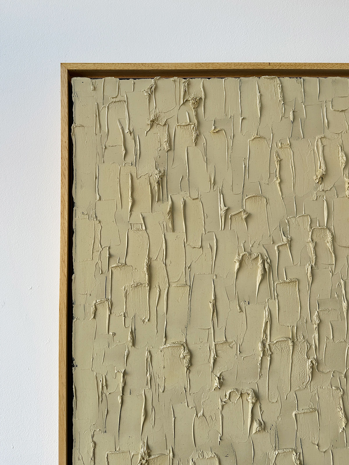 A close-up of Roi Elmaliah’s 'Buff Titanium'—a heavy texture oil on canvas—shows thick beige brushstrokes in vertical and horizontal patterns, framed in simple light wood.