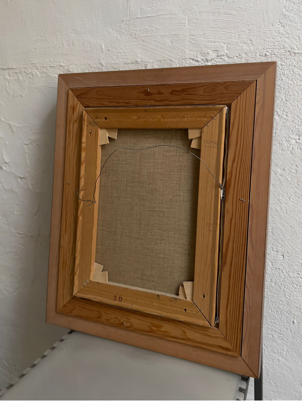 A Still Life Painting by Jan Palmu (Finland, 1986) from Veter Vintage is displayed from the back, showing its canvas and stretcher bars on a white bench against a textured white wall.