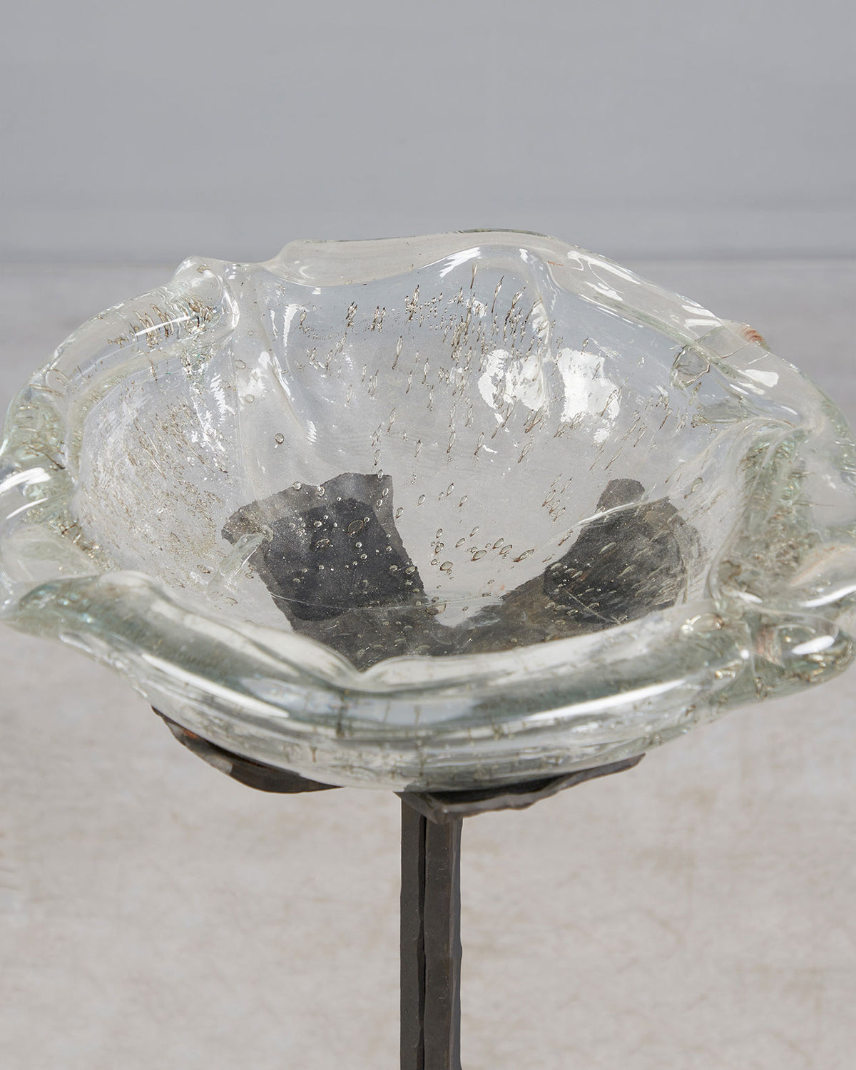 Close-up detail of brutalist iron candle stand with glass bowl