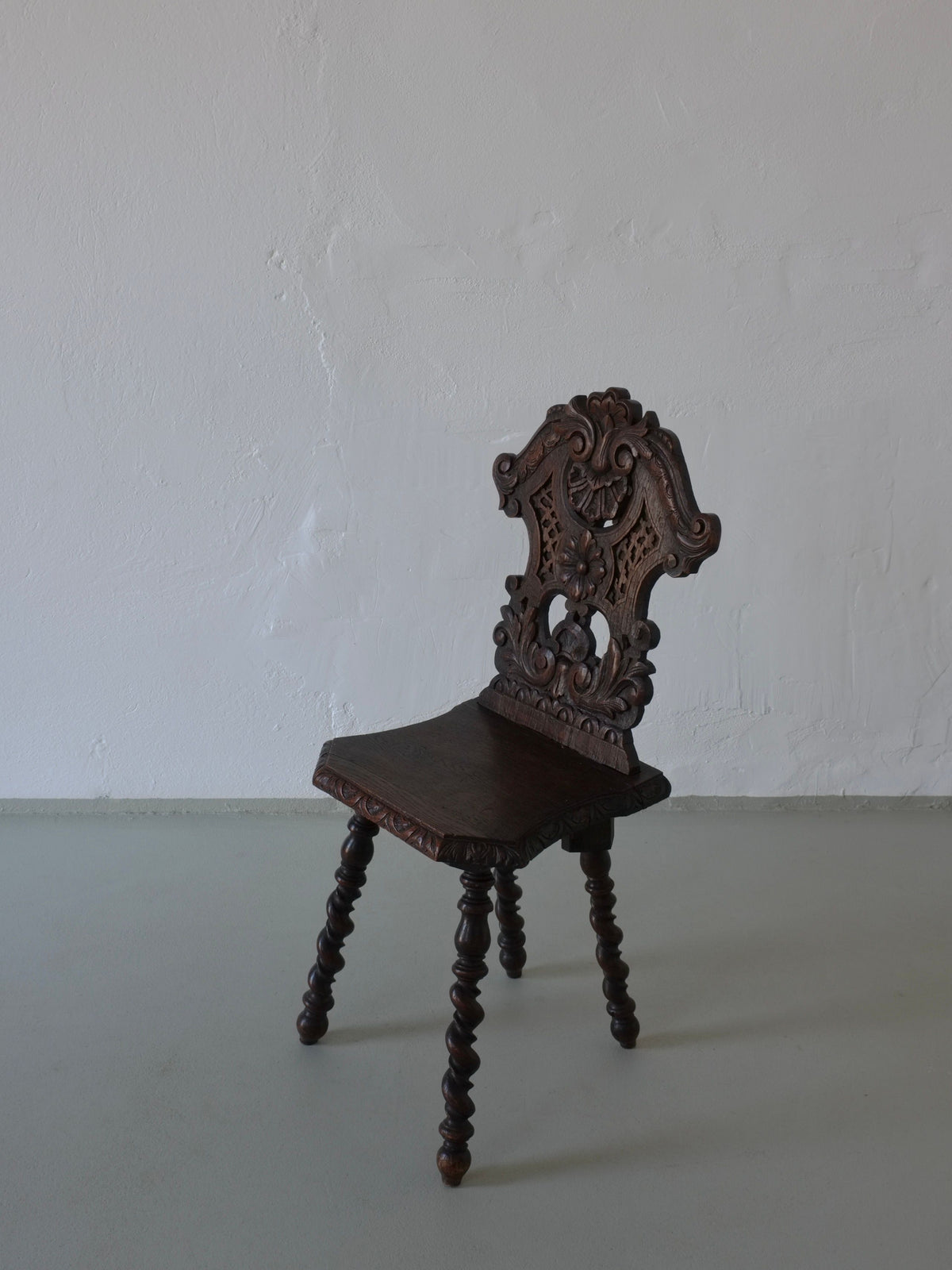 Ornate carved dark oak chair backrest detail showing decorative motifs