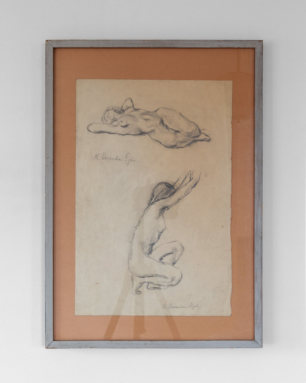 The Spigel "Nude Drawing Study I, 1940s" is a framed artwork showcasing two vintage sketches by Harriet Rosander de Tourtchaninoff. The top sketch captures a reclining figure with arms folded over their head, and the bottom portrays a seated female form study stretching with arms raised. Both drawings are on aged paper and are signed by the artist.