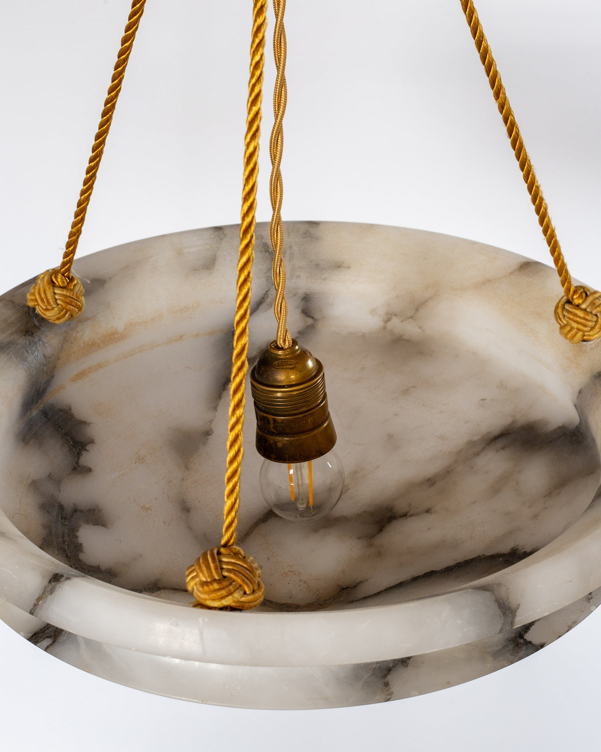 The Spigel Art Deco Diamond Alabaster Pendant features a round, marble-patterned shade and gold cords with an exposed bulb, creating striking statement lighting against a plain white background.