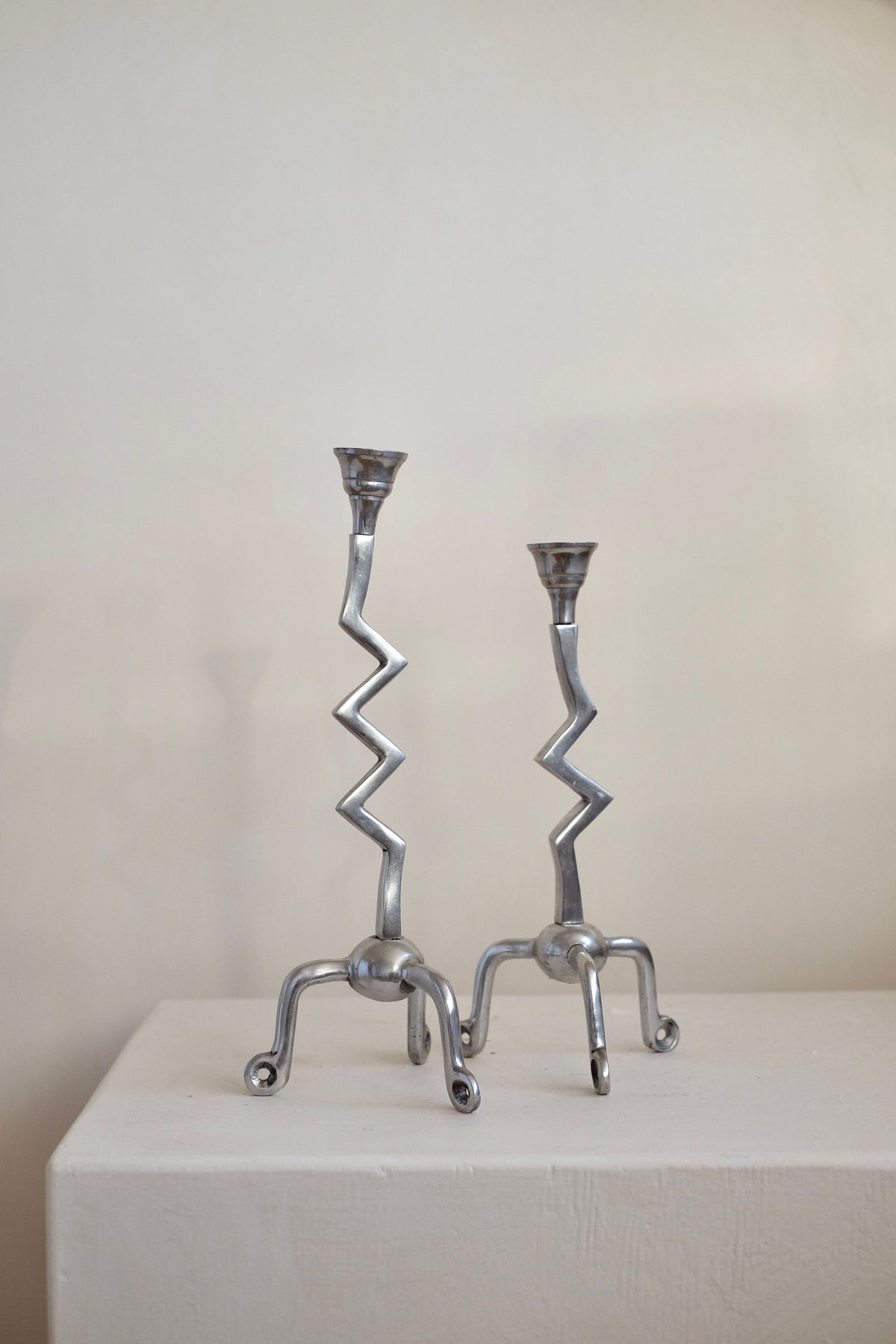 A pair from the Set of Zigzag Candleholders by septembre studios is displayed on a white surface against a simple, light backdrop. Their rare design features zigzag stems and claw-like bases, offering an abstract and artistic look reminiscent of vintage zilver craftsmanship.