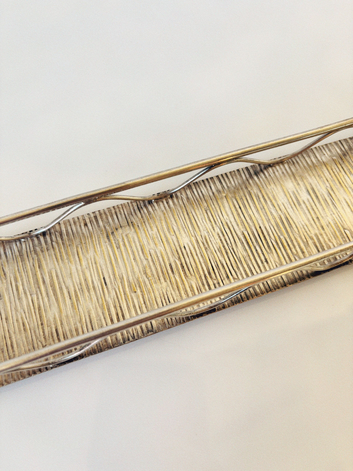The 60's Liquor Server Set by Imago Artis from Huerto features a rectangular wicker tray with a metal frame and raised edges, exuding vintage charm on a plain white surface.