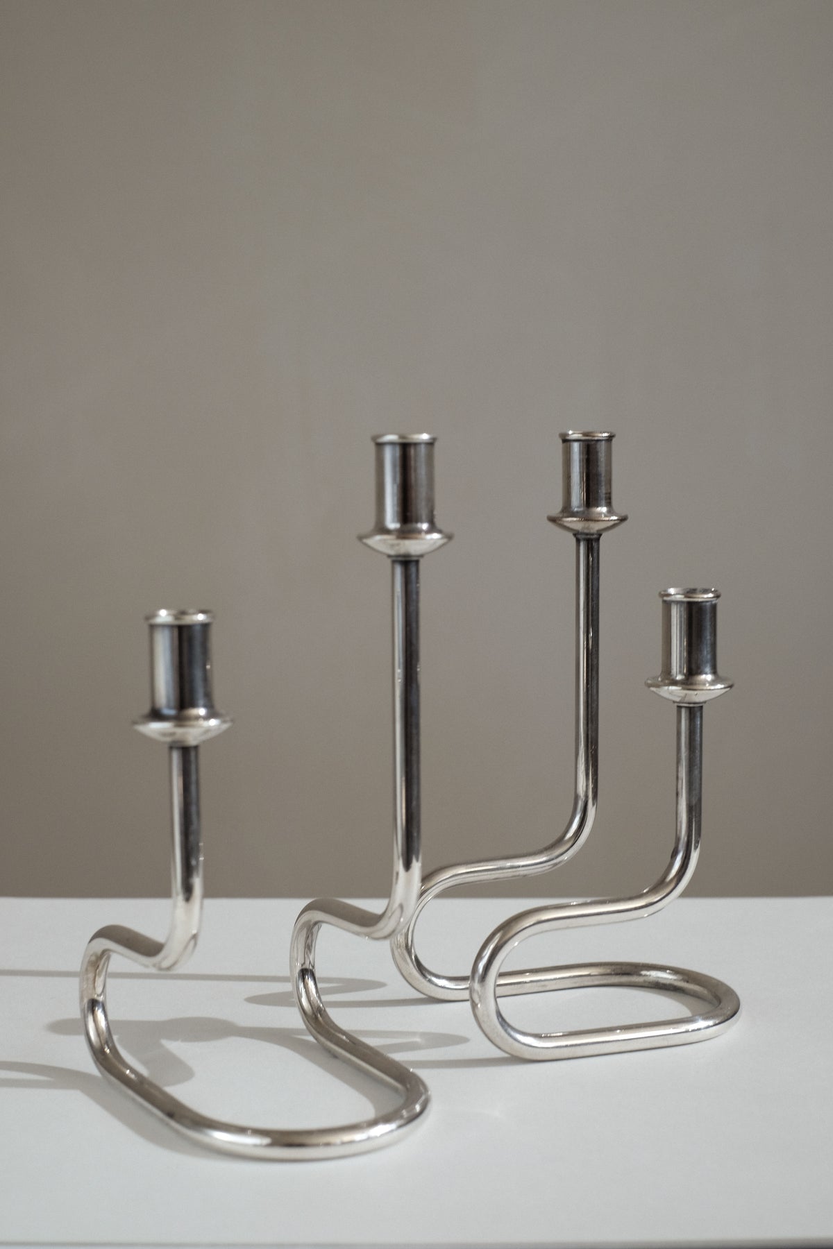Pair of polished steel Italian candleholders with curved bases