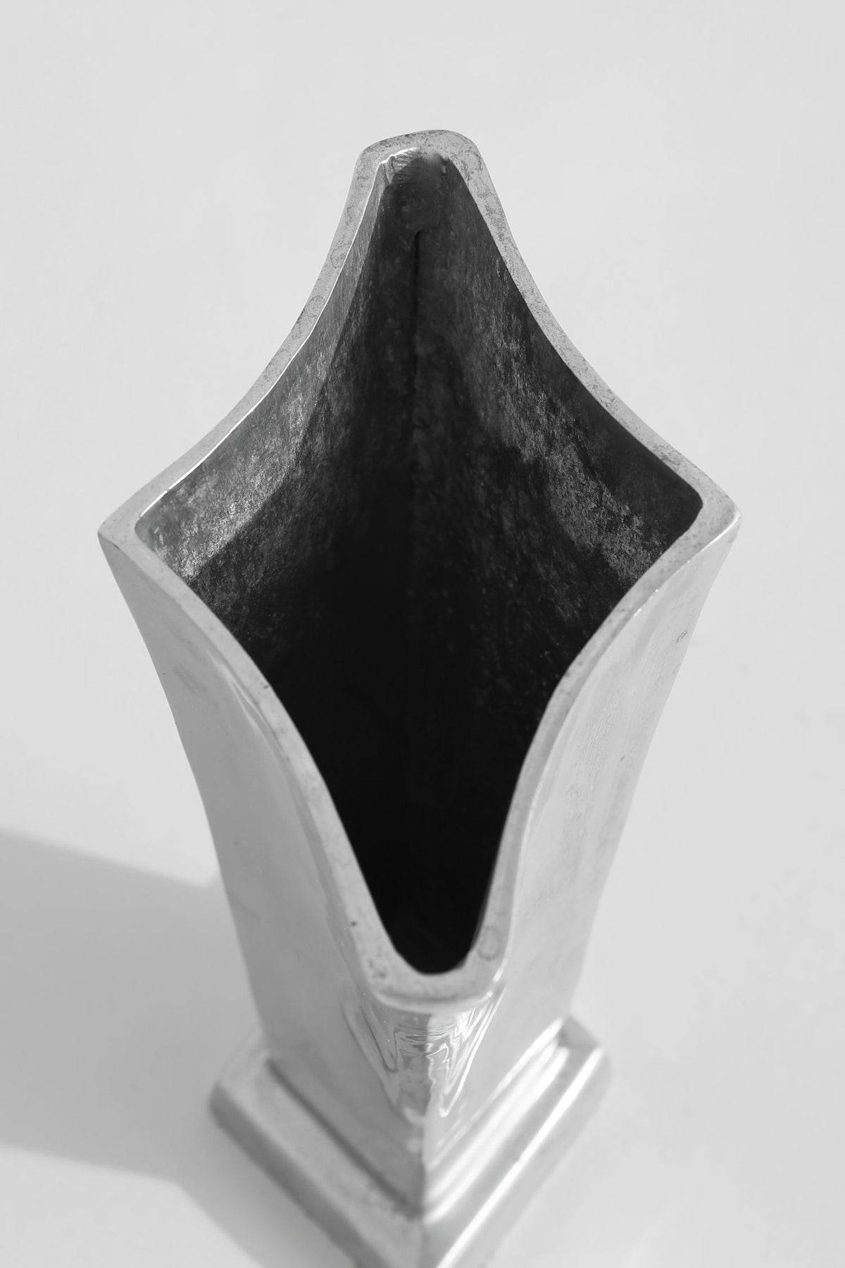 Chrome tulip vase interior view showing dark curved cavity detail