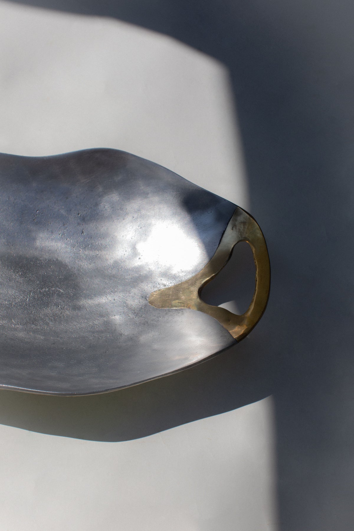 Hammered metal brutalist bowl with curved handle detail