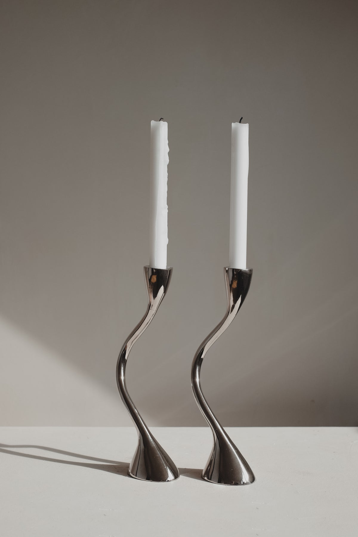 Pair of chrome zigzag candleholders with white candles, 1970s design