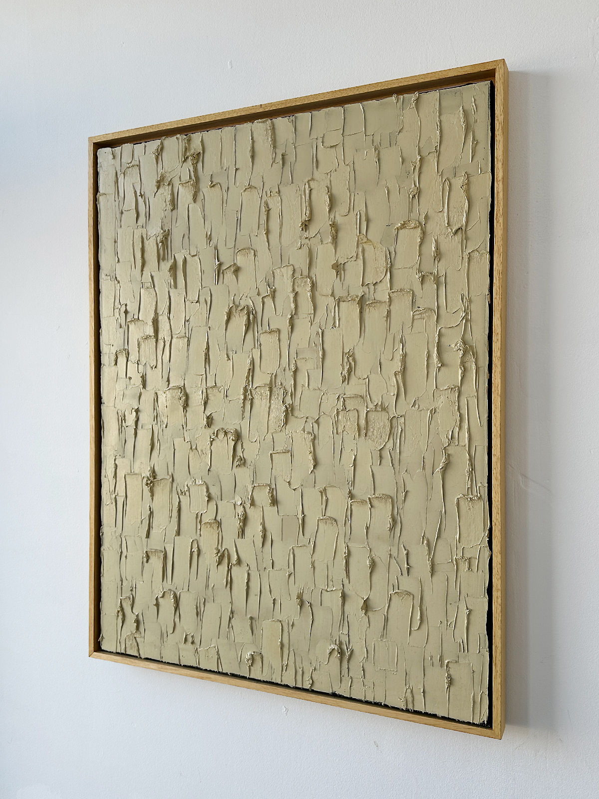 'Buff Titanium' - Heavy Texture by Roi Elmaliah is a framed abstract oil on canvas featuring a beige, textured surface with uneven raised patches and ridges, displayed against a white wall.