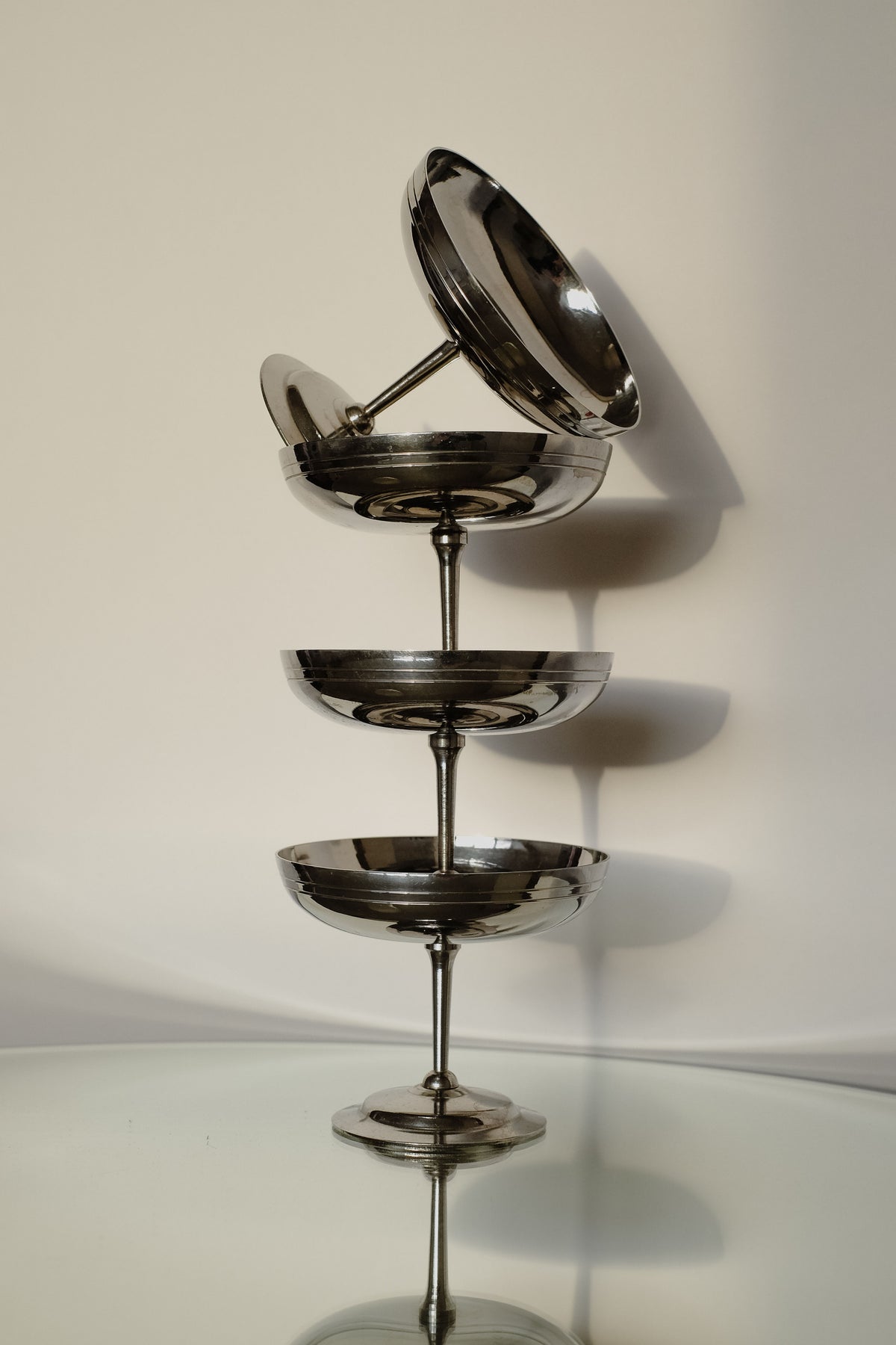 A set of four Ice Coupes by septembre studios, made in France, is arranged vertically on a reflective glass surface, casting shadows on a light-colored wall. The varying sizes create an elegant and modern display, perfect for serving ice cream with style.
