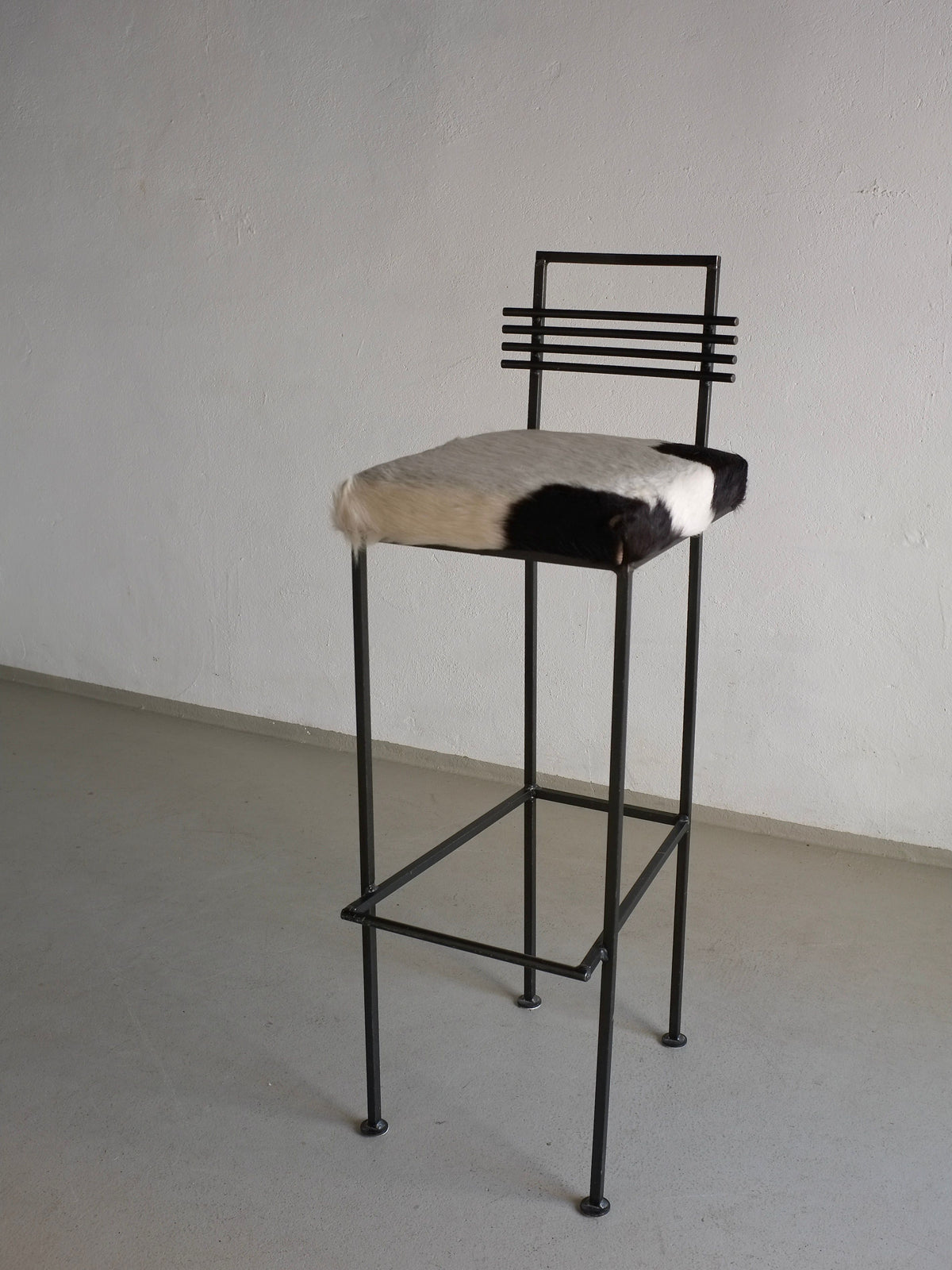 Modern wrought iron bar stool with cowhide seat and linear backrest