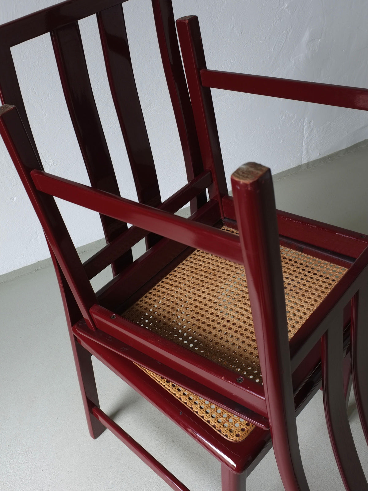 Close-up view of stacked wine red cane seat chairs showing detail
