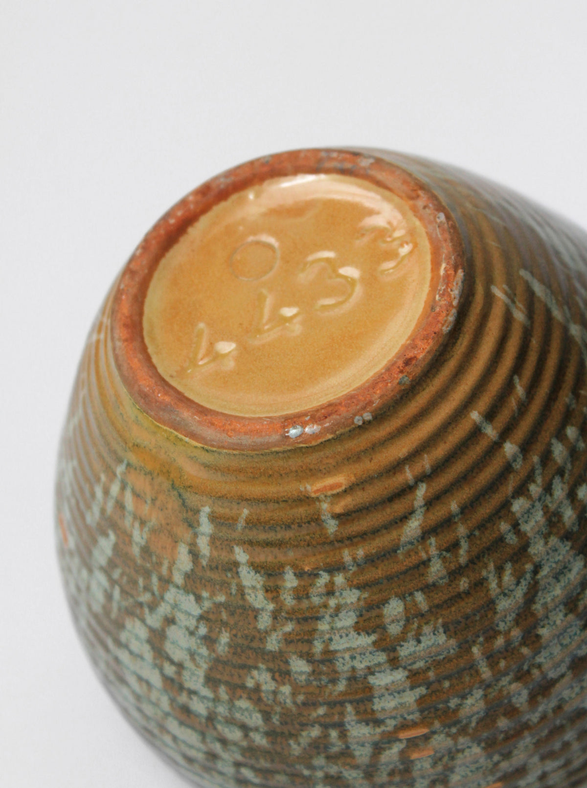 Bottom view showing ceramic base with horizontal ridged pattern and maker's mark