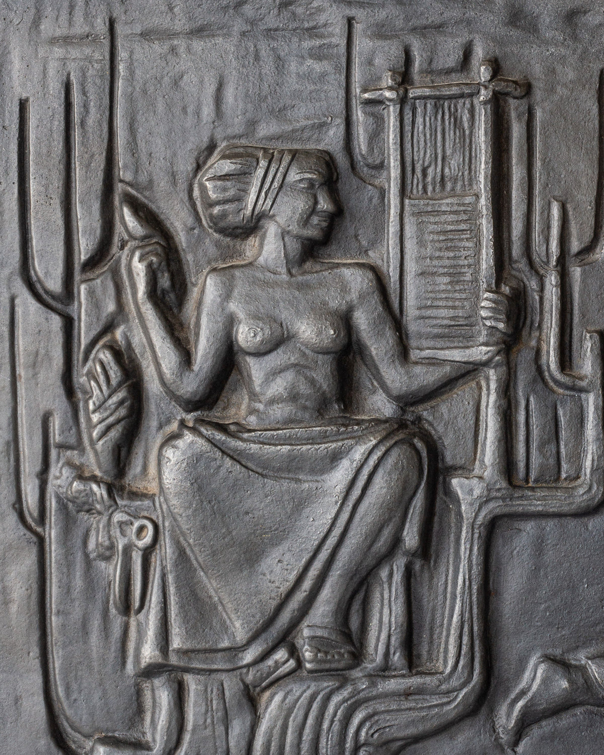 Cast iron wall relief depicting seated figure with musical instrument