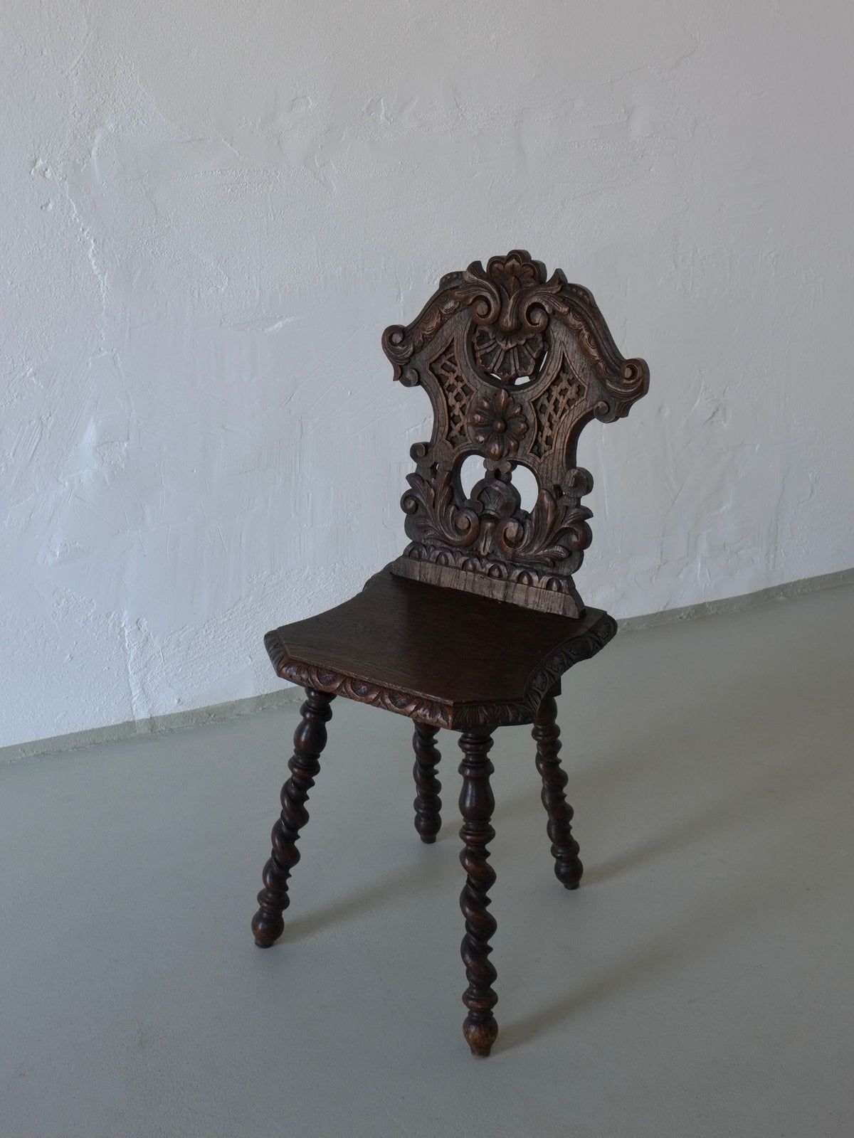 Ornate carved back detail of antique dark oak chair