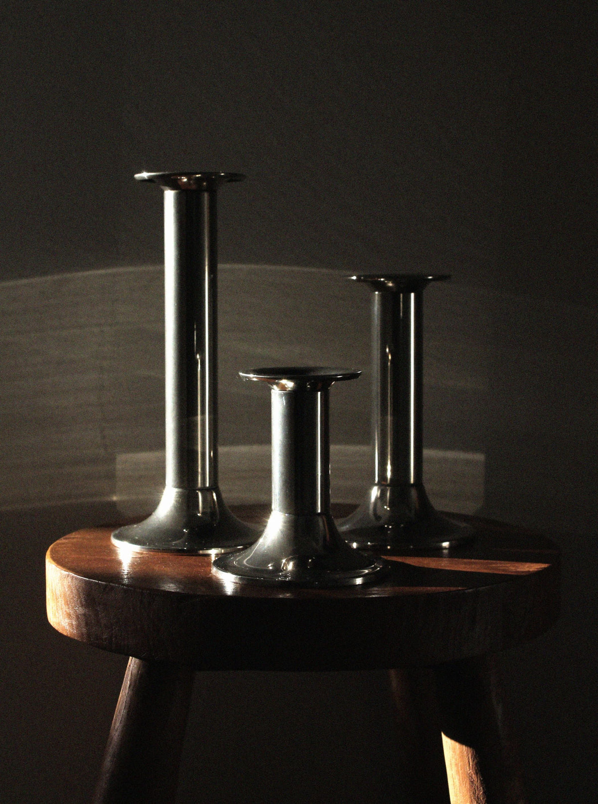 Three silver-plated vintage candle holders on wooden table
