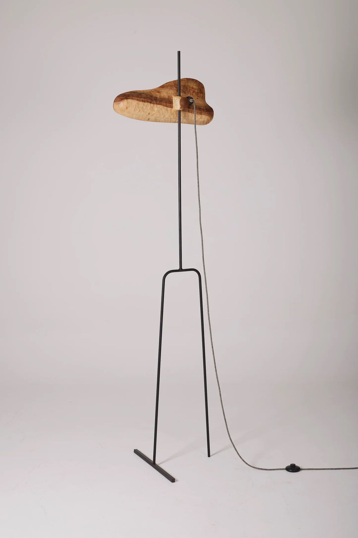 Sculptural walnut Oiseau floor lamp on black metal stand, side view