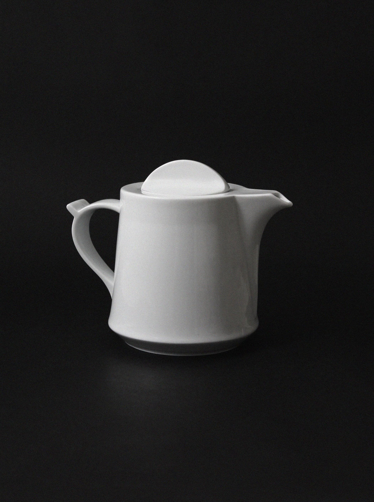 White porcelain teapot with dome lid on dark background