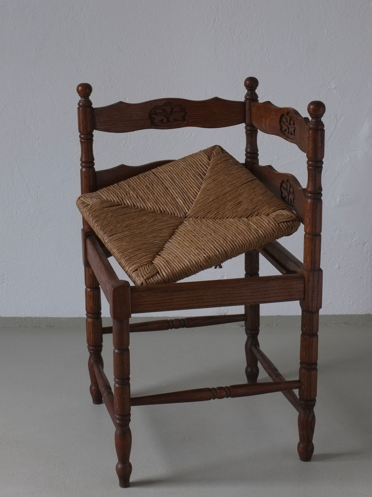 Carved oak corner chair with rush seat showing decorative details