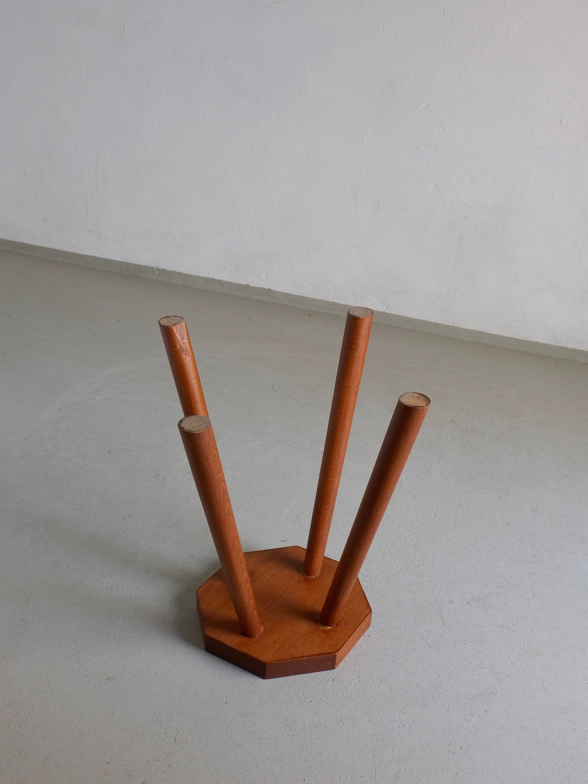 A small, vintage Veter Vintage Solid Wood Octagonal Stool from the 1960s in Belgium is shown upside down on a light-colored floor against a plain white wall. The stool features an octagonal seat with four cylindrical legs extending upwards, and its simple design emphasizes the natural wood texture.