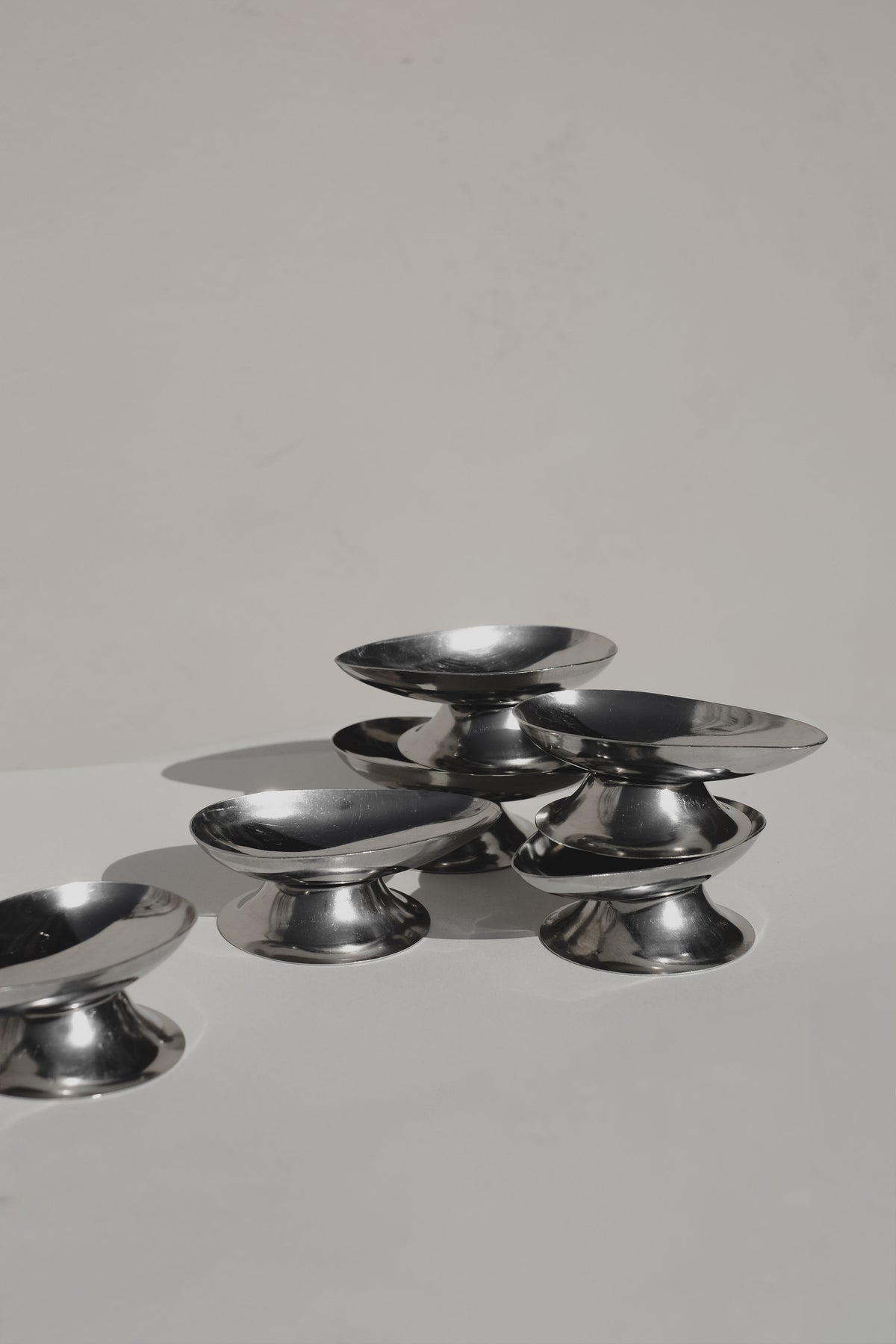 Set of six polished steel ice coups arranged on white surface
