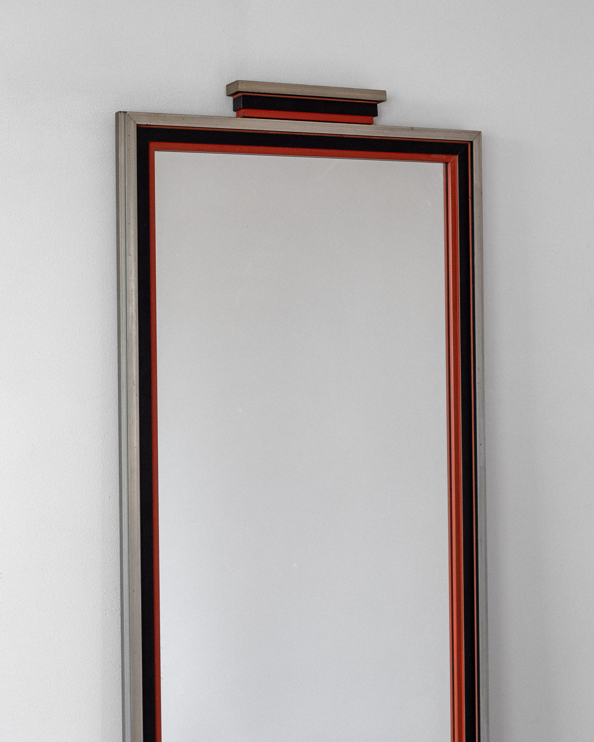 The Art Deco Mirror by Spigel, crafted in Sweden during the 1930s, is tall and rectangular with a thin black frame accented by a red inner border. Mounted on a white wall, it features a small decorative shelf at the top—exuding J.A. Edenholm’s timeless design style.