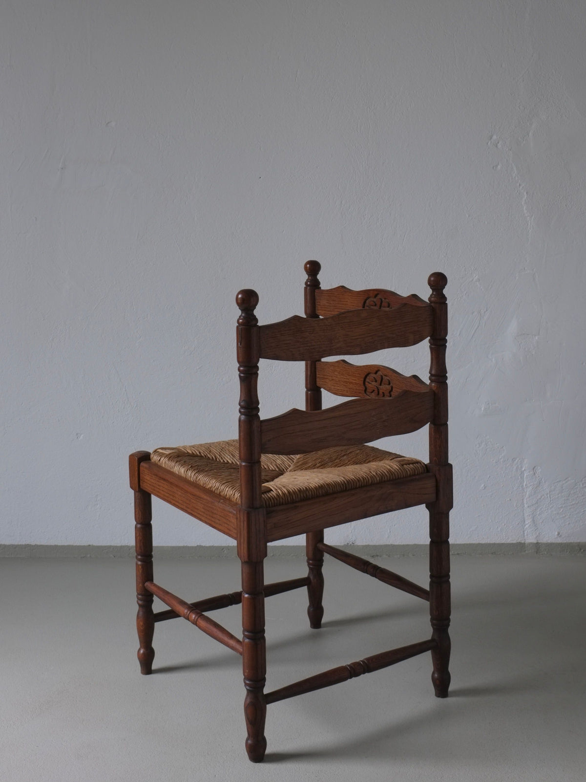 Oak corner chair with woven rush seat and carved back details