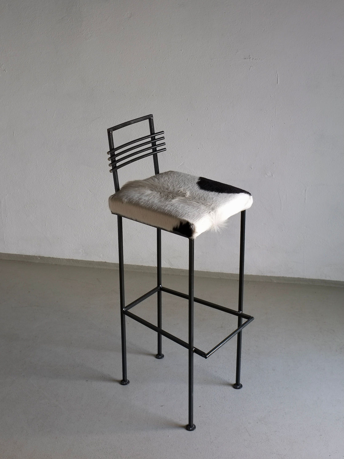 Modern wrought iron bar stool with cowhide seat and linear backrest